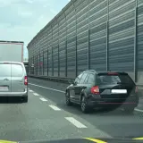 Kork na autostradzie, samochody stoją w rzędzie. Kierowcy czekają na możliwość jazdy na suwak, by płynnie włączyć się do ruchu.