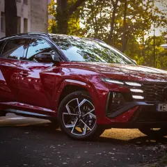 Czerwony Hyundai Tucson hybryda zaparkowany przy ulicy, oświetlony zachodzącym słońcem.
