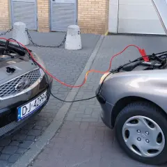 Kable rozruchowe łączą dwa samochody. Czerwony to plus, czarny minus. Pomoc w awaryjnej sytuacji.