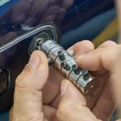 Specjalista manipuluje zamkiem, by otworzyć auto. Dowiedz się, ile kosztuje awaryjne otwieranie samochodu.