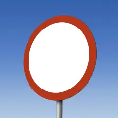 Pusty okrągły znak drogowy z czerwoną obwódką, przypominający znak B1, na tle błękitnego nieba.