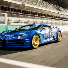 Niebieski Bugatti Centodieci z numerem 34 i złotymi felgami pędzi po torze wyścigowym.