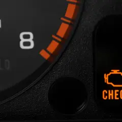 Pomarańczowa kontrolka "CHECK ENGINE" świeci na desce rozdzielczej, sygnalizując potencjalne kody błędów w samochodzie.