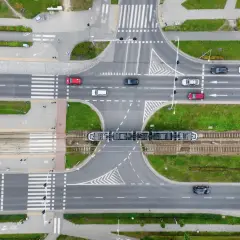 Widok z góry na skrzyżowanie z tramwajem i samochodami. Zastanawiasz się, ile metrów od skrzyżowania można parkować? Przepisy drogowe określają to precyzyjnie.