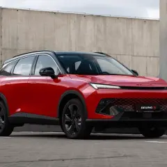 Czerwony BAIC 5, SUV o futurystycznym designie, prezentuje swoje pięć wymiarów na tle betonowej ściany.