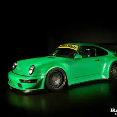 Jaskrawozielone Porsche RWB z szerokimi błotnikami i charakterystycznym skrzydłem, gotowe do wyścigu.