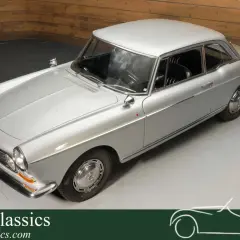 Elegancki, srebrny Peugeot 404 coupe z lat 60. na obrotowej platformie. Klasyka motoryzacji.
