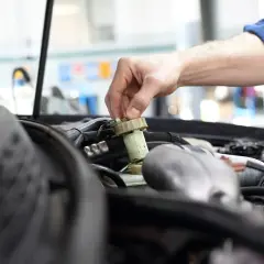 Mechanik sprawdza płyn hamulcowy. Czas na badanie techniczne po terminie, by uniknąć problemów.