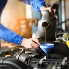 Mechanik wlewa olej do silnika. Pamiętaj o regularnej wymianie oleju, co ile to konieczne dla sprawnego działania auta.
