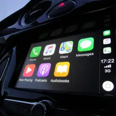 Ekran samochodu z ikonami: Telefon, Muzyka, Mapy, Wiadomości, Odtwarzanie, Podcasty, Audiobooki. To jest właśnie co to jest CarPlay.