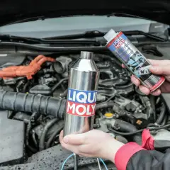 Ręce trzymają preparaty Liqui Moly do czyszczenia układu paliwowego, by zapobiec objawom zapchanego katalizatora.