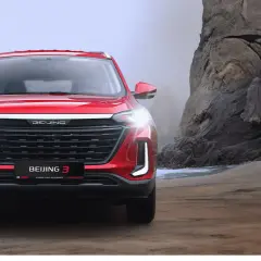Czerwony beijing samochód na tle skalistej plaży.