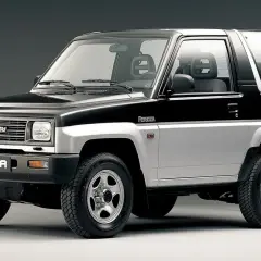 Dwukolorowy Daihatsu Feroza, klasyczny samochód terenowy z lat 90., prezentuje się na szarym tle.