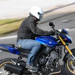 Motocyklista w białym kasku pędzi na niebieskim motocyklu Yamaha FZ8.