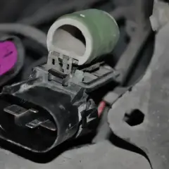 Zielony opornik ceramiczny z metalowymi zaciskami, podłączony do złącza elektrycznego.