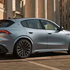Srebrny Maserati Grecale z eleganckimi felgami stoi na brukowanej ulicy przed zabytkową kamienicą.