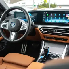 Wnętrze BMW M440i z brązową skórzaną tapicerką, dużym ekranem multimedialnym i cyfrowymi zegarami.