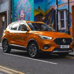 Pomarańczowy MG ZS Classic na tle kolorowego muralu.