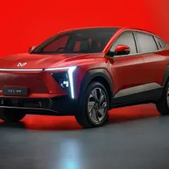 Czerwony, elektryczny SUV Mahindra XUV 9e z futurystycznym designem i podświetlanym grillem.
