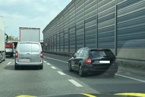 Kork na autostradzie, samochody stoją w rzędzie. Kierowcy czekają na możliwość jazdy na suwak, by płynnie włączyć się do ruchu.