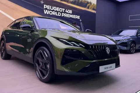 Nowy Peugeot 408 w kolorze zielonym prezentuje się na premierze światowej. Obok stoi niebieski egzemplarz.