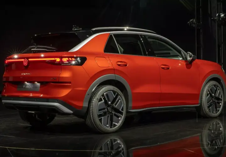 Pomarańczowy Volkswagen T-Roc z czarnym dachem, nowoczesnymi światłami LED i stylowymi felgami. Sprawdź aktualną volkswagen t-roc cena.