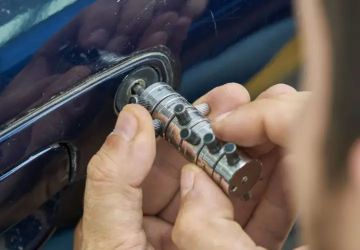 Specjalista manipuluje zamkiem, by otworzyć auto. Dowiedz się, ile kosztuje awaryjne otwieranie samochodu.