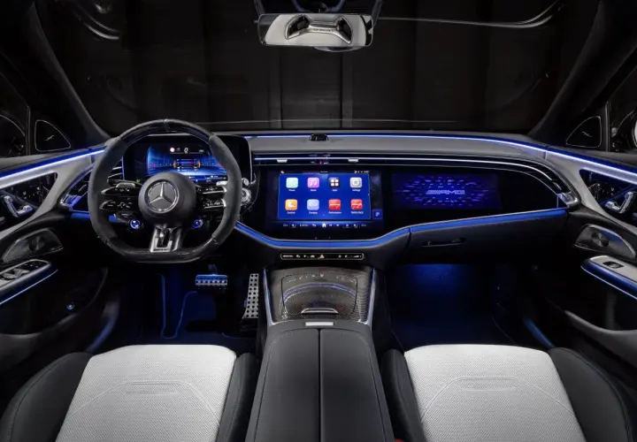 Wnętrze e53 AMG z podświetlanymi na niebiesko detalami, dużymi ekranami i sportową kierownicą.