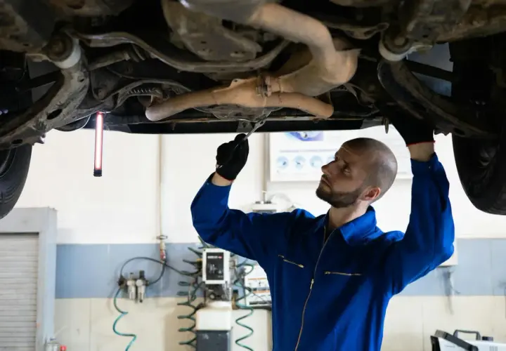 Mechanik sprawdza podwozie Audi, szukając przyczyny błędu DTC P0420.