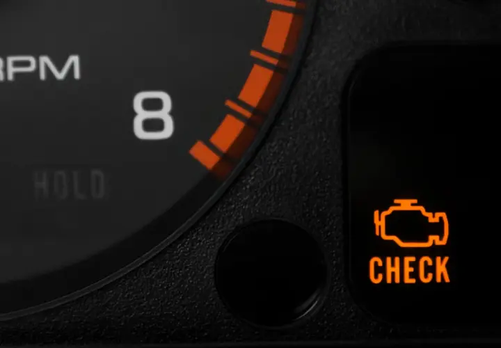 Pomarańczowa kontrolka "CHECK ENGINE" świeci na desce rozdzielczej, sygnalizując potencjalne kody błędów w samochodzie.