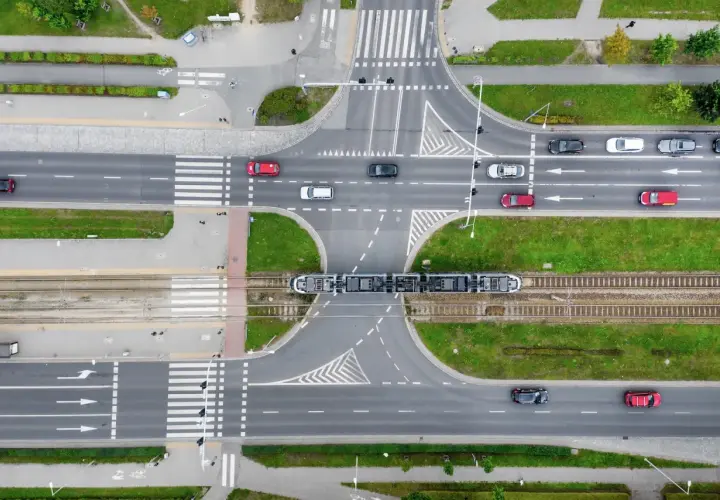 Widok z góry na skrzyżowanie z tramwajem i samochodami. Zastanawiasz się, ile metrów od skrzyżowania można parkować? Przepisy drogowe określają to precyzyjnie.