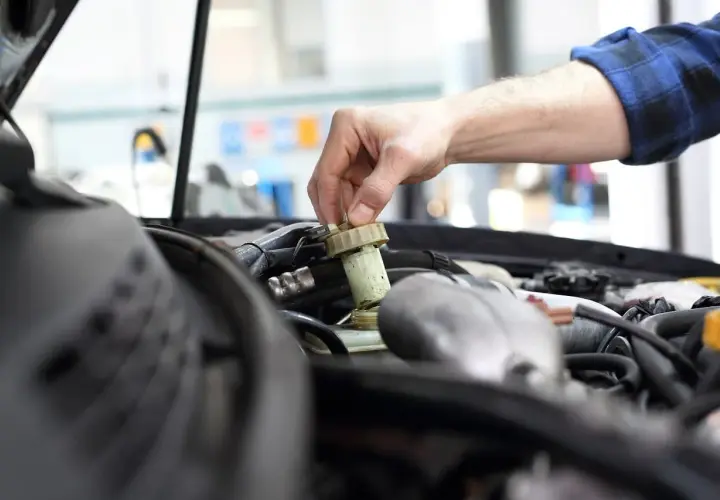 Mechanik sprawdza płyn hamulcowy. Czas na badanie techniczne po terminie, by uniknąć problemów.