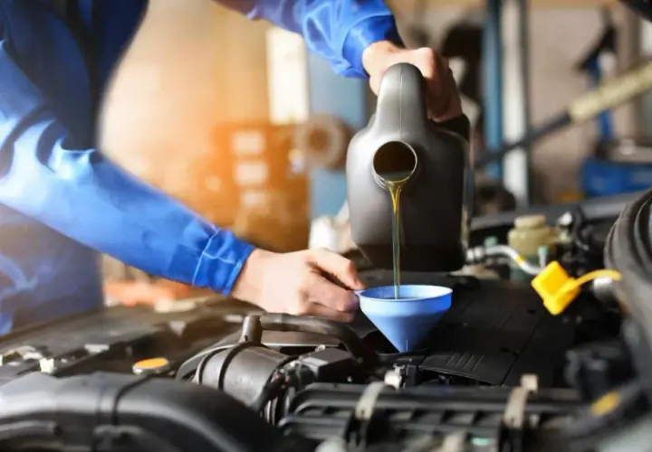 Mechanik wlewa olej do silnika. Pamiętaj o regularnej wymianie oleju, co ile to konieczne dla sprawnego działania auta.
