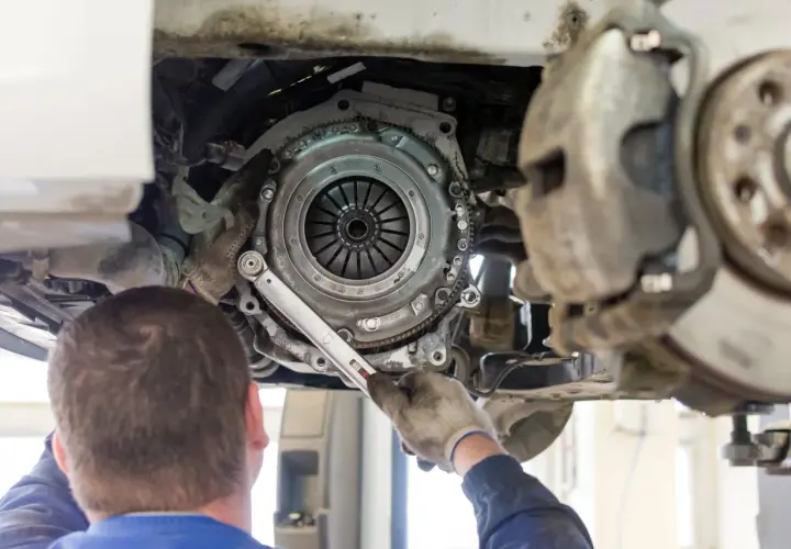 Mechanik dokonuje wymiany sprzęgła w samochodzie, używając klucza dynamometrycznego do precyzyjnego dokręcenia śrub.