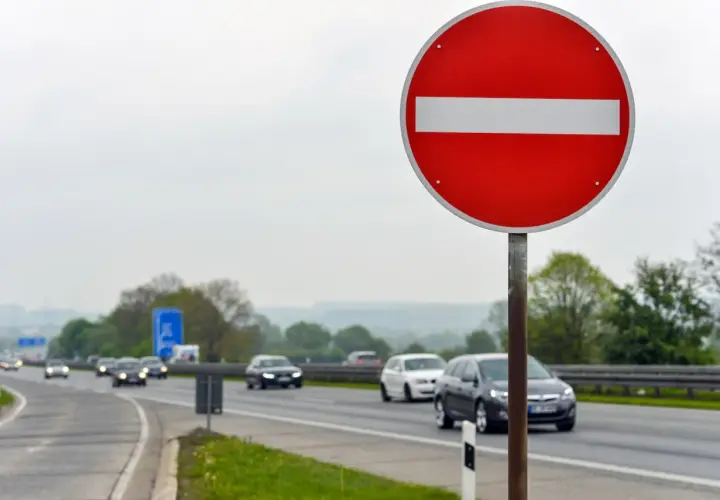 Znak "zakaz wjazdu" ostrzega przed niebezpieczną jazdą pod prąd. Ryzyko mandatu i wypadku jest wysokie.