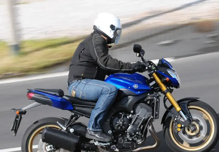 Motocyklista w białym kasku pędzi na niebieskim motocyklu Yamaha FZ8.