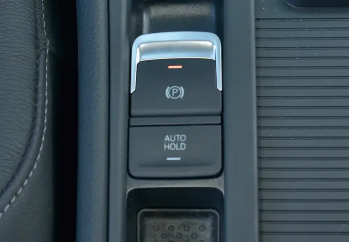 Przycisk "AUTO HOLD" w samochodzie, obok hamulca ręcznego.