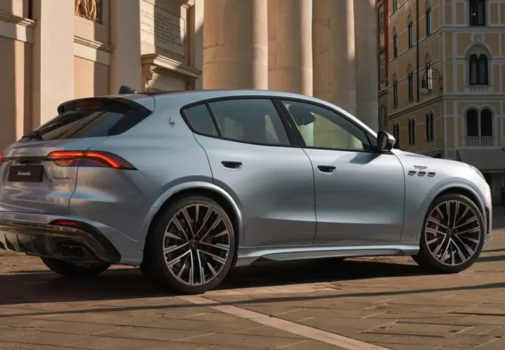 Srebrny Maserati Grecale z eleganckimi felgami stoi na brukowanej ulicy przed zabytkową kamienicą.
