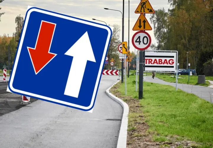Znak D5 z białymi strzałkami, jedna w górę, druga w dół, na niebieskim tle. Obok znaki drogowe i tablica "TRABAG".