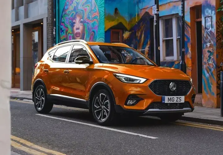 Pomarańczowy MG ZS Classic na tle kolorowego muralu.