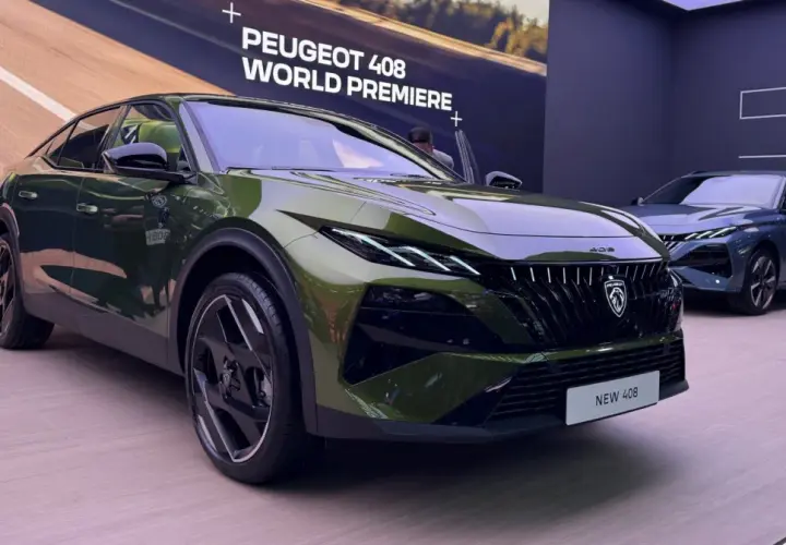 Nowy Peugeot 408 w kolorze zielonym prezentuje się na premierze światowej. Obok stoi niebieski egzemplarz.