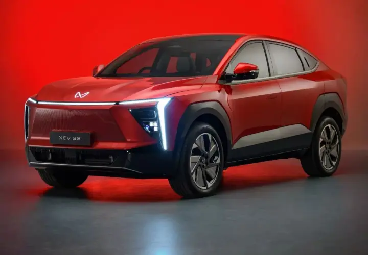 Czerwony, elektryczny SUV Mahindra XUV 9e z futurystycznym designem i podświetlanym grillem.