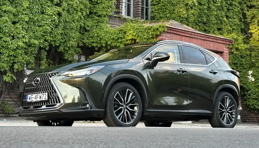 Elegancki, ciemnozielony Lexus NX 450h+ na tle zielonej ściany z cegły. Sprawdź jego atrakcyjną lexus nx 450h+ cenę!