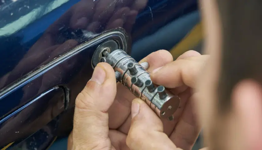 Specjalista manipuluje zamkiem, by otworzyć auto. Dowiedz się, ile kosztuje awaryjne otwieranie samochodu.