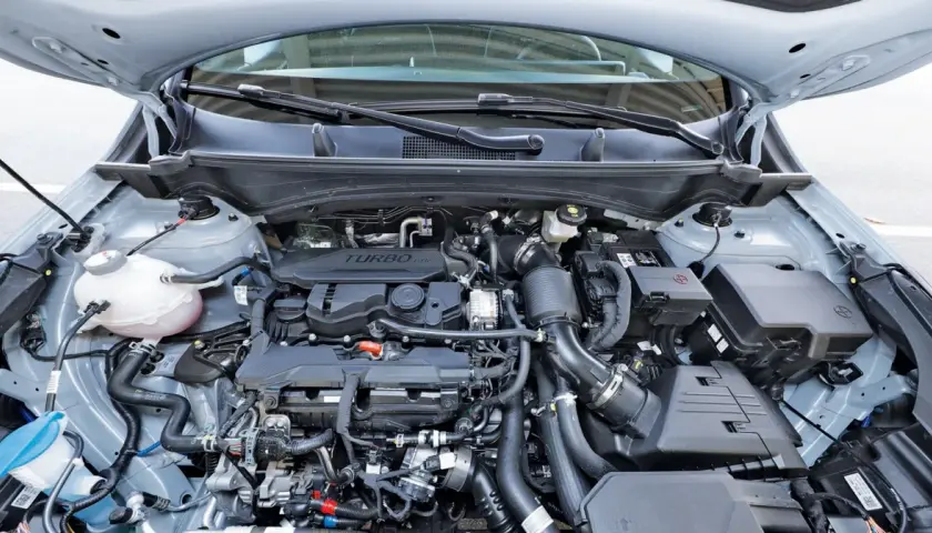 Silnik 1.6 GDI Turbo w samochodzie z otwartą maską. Widoczne przewody, turbosprężarka i inne elementy jednostki napędowej.