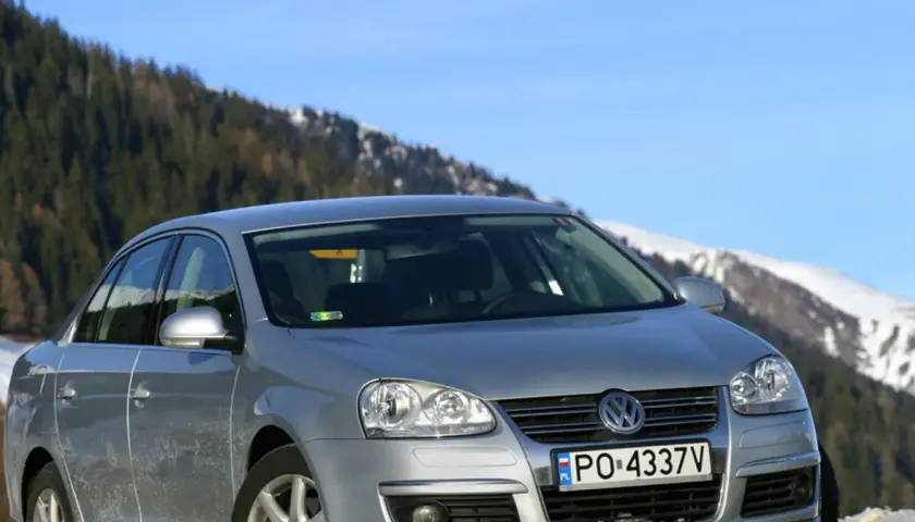Srebrna Jetta MK5 na tle ośnieżonych gór i lasu.