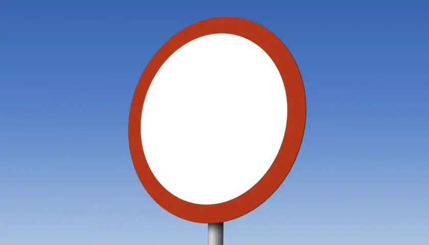 Pusty okrągły znak drogowy z czerwoną obwódką, przypominający znak B1, na tle błękitnego nieba.