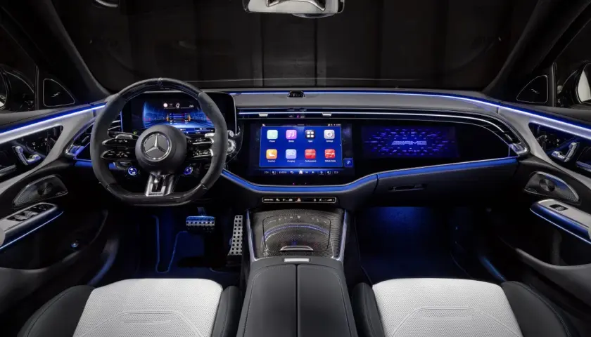 Wnętrze e53 AMG z podświetlanymi na niebiesko detalami, dużymi ekranami i sportową kierownicą.