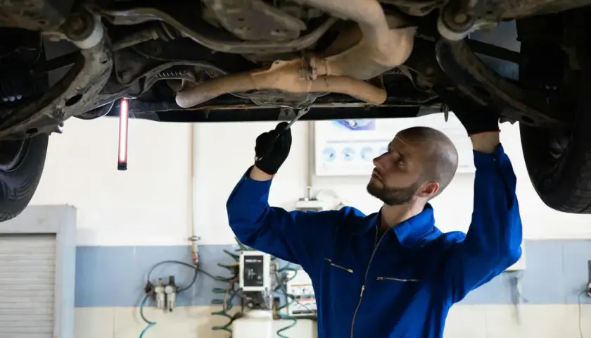Mechanik sprawdza podwozie Audi, szukając przyczyny błędu DTC P0420.