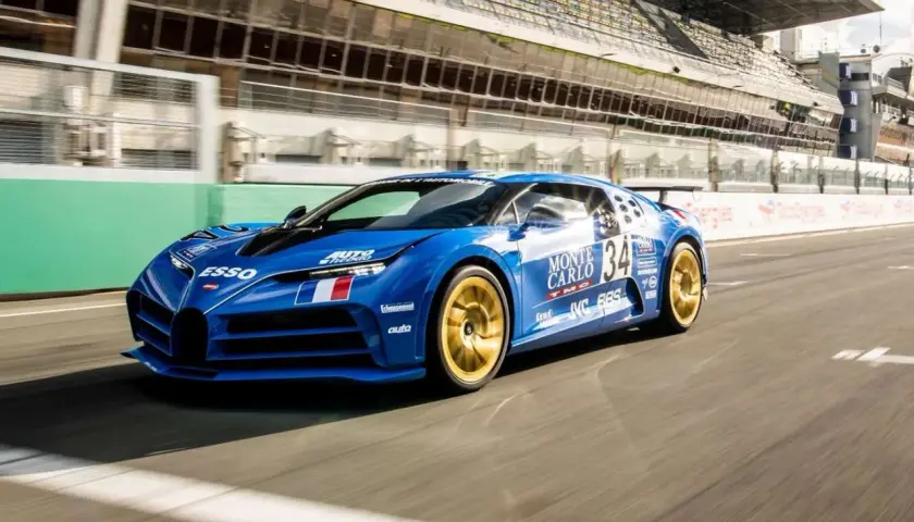 Niebieski Bugatti Centodieci z numerem 34 i złotymi felgami pędzi po torze wyścigowym.